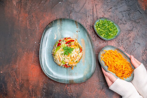 어두운 테이블에 얇게 썬 당근과 채소를 넣은 접시 안에 있는 신선한 야채 샐러드