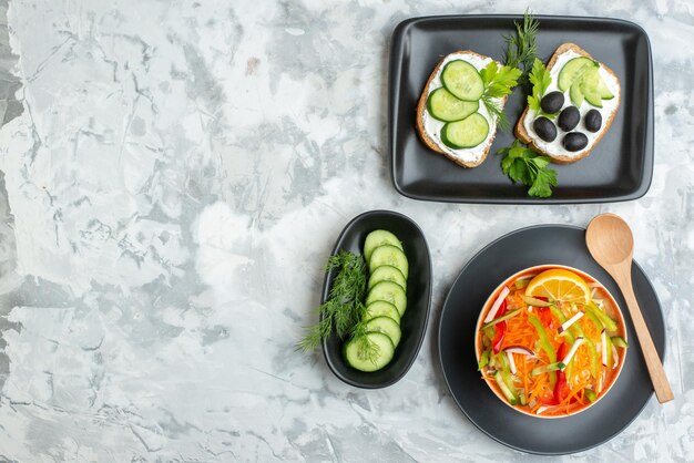 Вид сверху салат из свежих овощей с огурцами и бутербродами на белой поверхности еда еда диета горизонтальный ужин здоровье