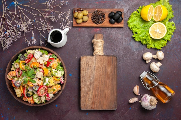 Vista dall'alto di verdura fresca. insalata con olive e fettine di limone su tavola nera