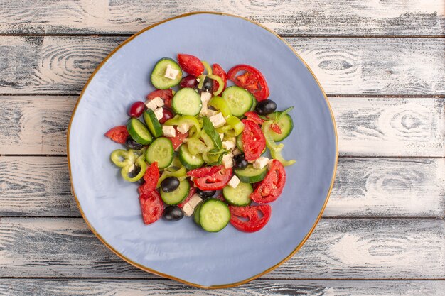 Top view fresh vegetable salad with sliced cucumbers tomatoes olive inside plate on grey surface vegetable food salad meal color