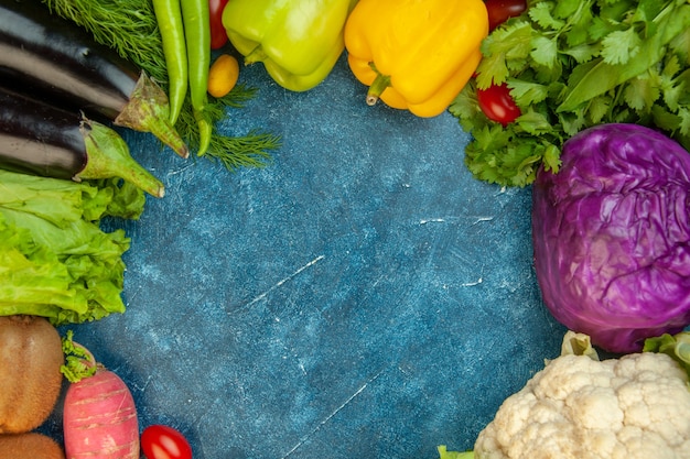 Top view fresh vegetables bell peppers quince cumcuats cauliflower red cabbage kiwi on blue background
