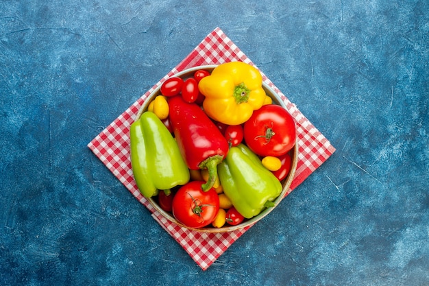 상위 뷰 신선한 야채 체리 토마토 다른 색상 피망 토마토 복사 공간이 파란색 테이블에 빨간색 흰색 체크 무늬 주방 수건에 플래터에 cumcuat