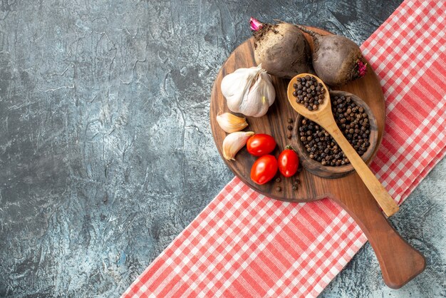 Top view fresh vegetables cherry tomatoes garlic beets black pepper in bowl on wood board on grey table free space