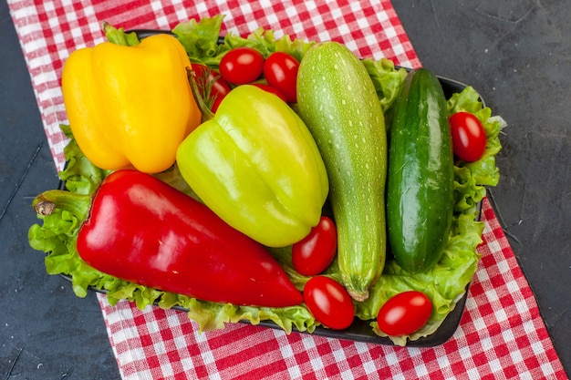 Top view fresh vegetables colorful bell peppers zucchini cherry tomatoes lettuce cucumber on dark table