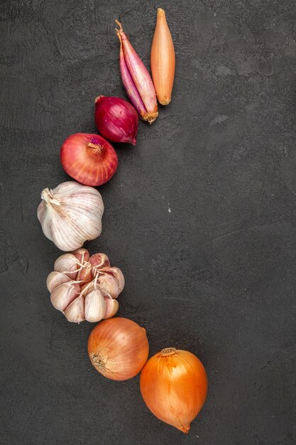 Top view fresh vegetables garlics and onions on grey background