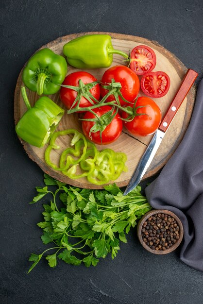 黒の苦しめられた表面のまな板緑の束のコショウの新鮮な野菜とナイフの上面図