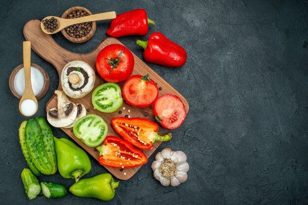 Top view fresh vegetables mushrooms red and green tomatoes bell peppers on chopping board