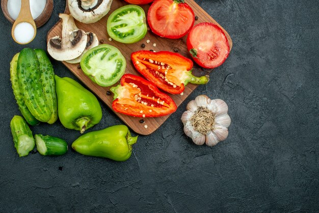 Free photo top view fresh vegetables mushrooms red and green tomatoes bell peppers on chopping board