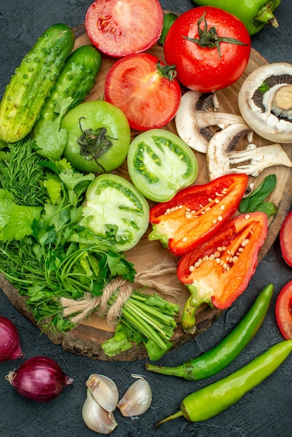 Free photo top view fresh vegetables mushrooms red and green tomatoes red bell peppers greens on rustic board