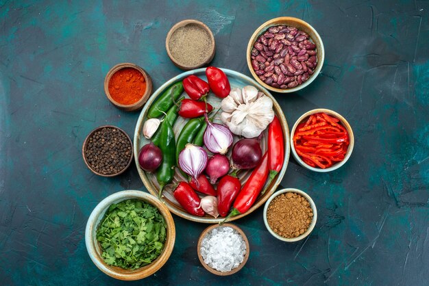 Top view of fresh vegetables onions garlic peppers with greens and beans on dark, food meal ingredient vegetable