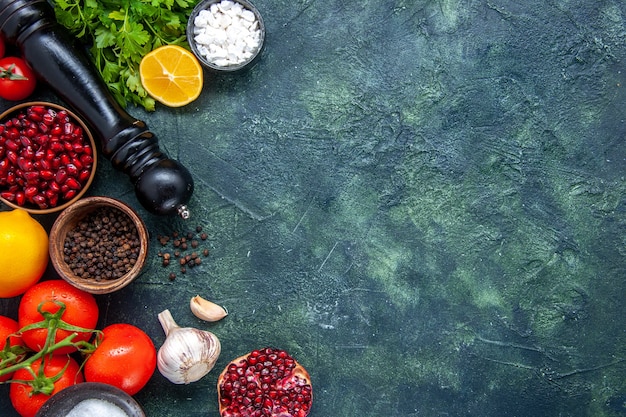 Free photo top view fresh vegetables pepper grinder tomatoes garlic greens pomegranate on table with copy place