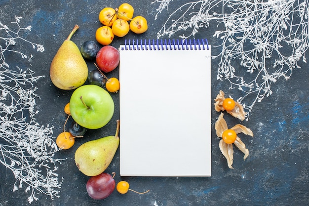 Top view of fresh vegetables such as pears green apple yellow cherries plums and notepad on dark desk, fruit fresh berry food