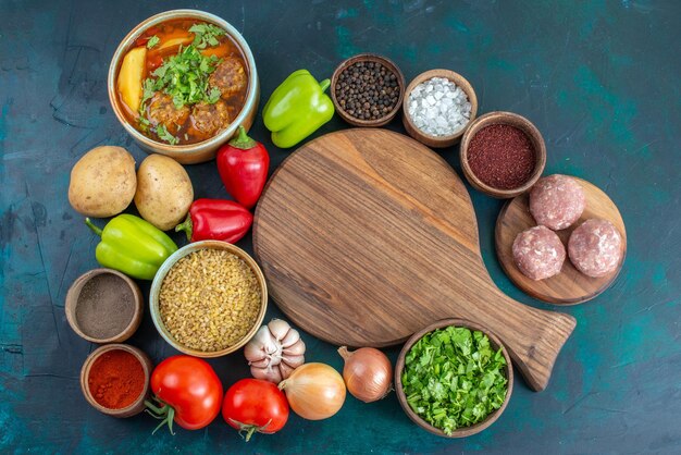 Top view fresh vegetables with different seasonings meat soup and greens on dark blue desk