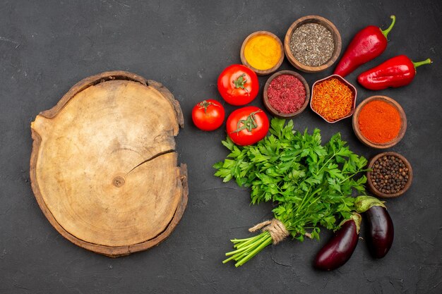 Top view of fresh vegetables with greens and seasonings on black