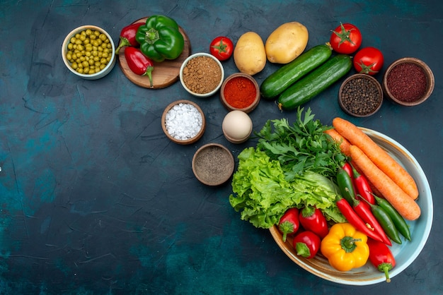 Free photo top view fresh vegetables with greens and seasonings on the dark-blue desk snack lunch salad vegetable food