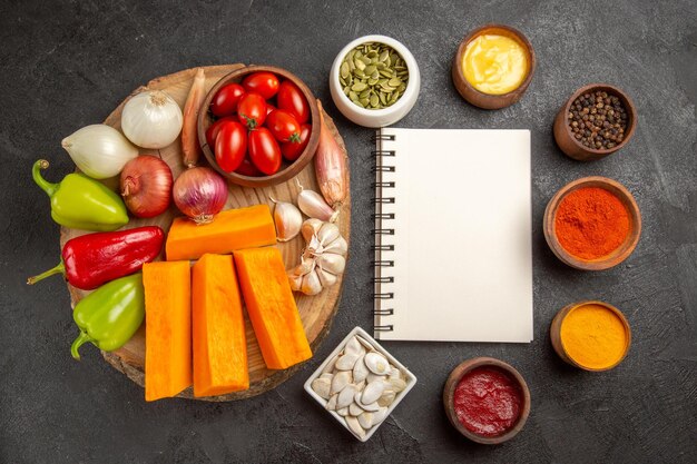 Top view fresh vegetables with pumpkin and seasonings on a dark background salad ripe meal color