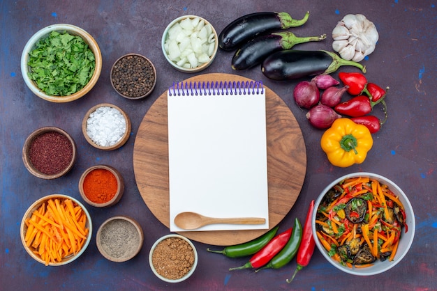 Top view fresh vegetables with salad and seasonings notepad on dark desk salad food meal vegetable snack