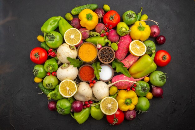 Top view fresh vegetables with seasonings on the dark background