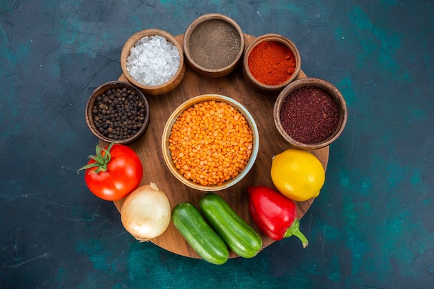 Free photo top view fresh vegetables with seasonings on dark blue background.