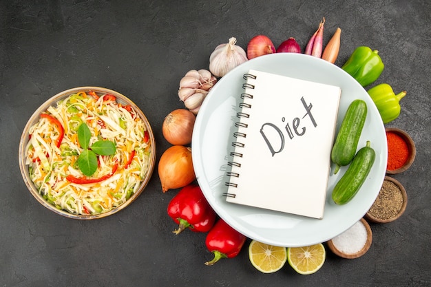 Free photo top view fresh vegetables with seasonings and diet writing on the grey background