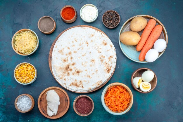 Top view fresh vegetables with seasonings and eggs on the dark-blue background.