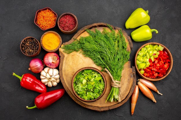 Вид сверху свежие овощи с приправами и зеленью на темной поверхности салат здоровые спелые овощи
