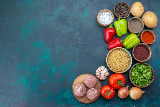 Top view fresh vegetables with seasonings meat and greens on dark-blue desk