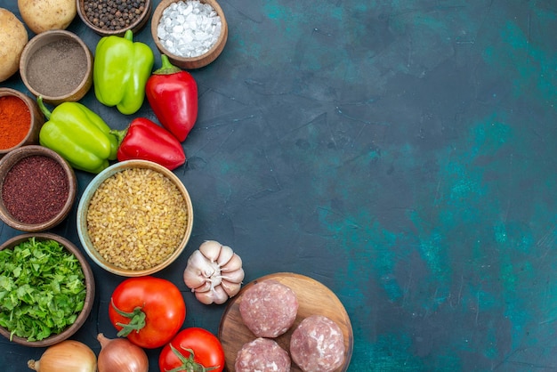 Top view fresh vegetables with seasonings meat and greens on dark blue desk