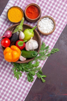 Вид сверху свежие овощи с приправами на темной поверхности спелый салат здоровая пища