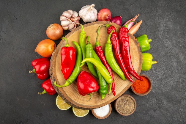 Top view fresh vegetables with seasonings and peppers on grey background