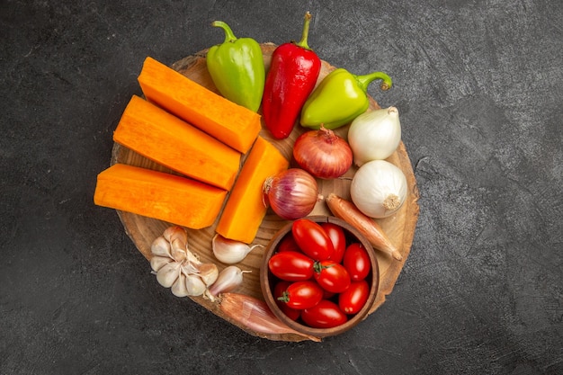 Top view fresh vegetables with sliced pumpkin on dark-grey background ripe color fresh