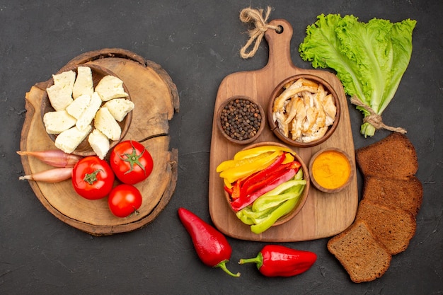 Top view of fresh vegetables with white cheese and black bread on black