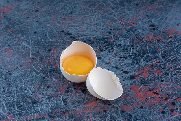 Вид сверху свежего белого куриного яйца, разбитого с желтком и яичным белком.