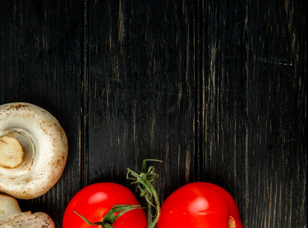 Top view of fresh white mushrooms and tomatoes on dark wood with copy space