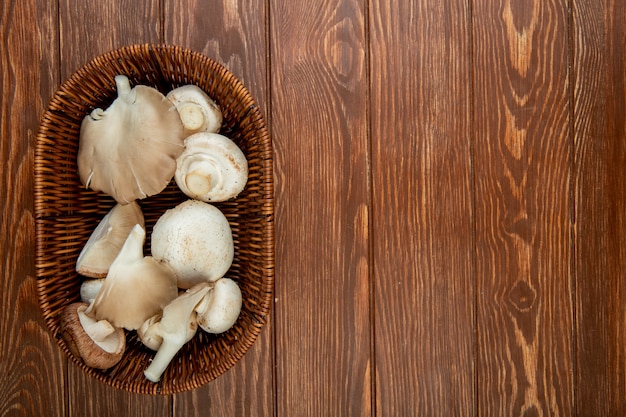 Top view of fresh white mushrooms in a wicker basket on rustic wood with copy space