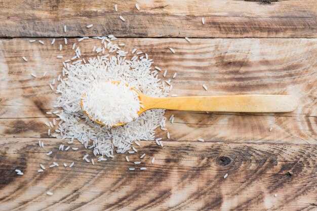 Взгляд сверху свежего белого риса разливая из деревянной ложки на деревянном столе