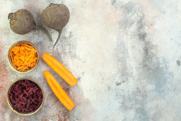 Top view of fresh whole and chopped beetroot and carrot on ice background