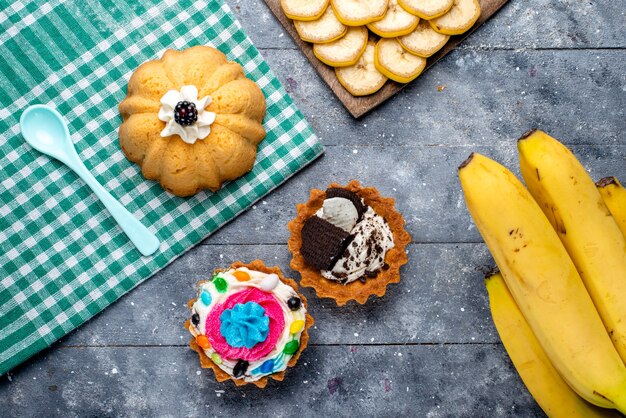 top view of fresh yellow bananas whole berries with cakes on light, fruit berry vitamine taste