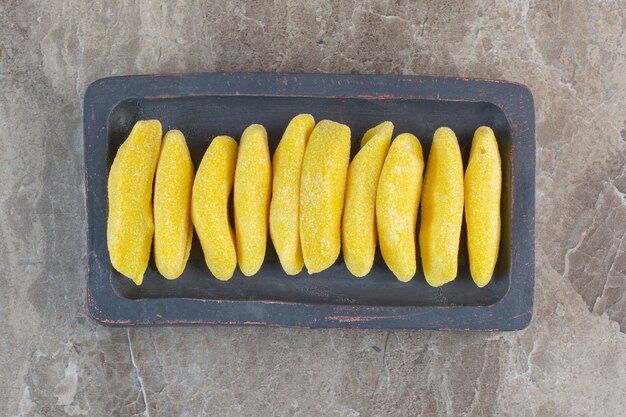 Top view of fresh yellow candies on wooden board .