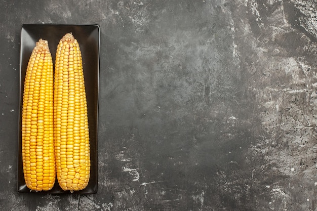 Top view fresh yellow corns inside black pan on dark background