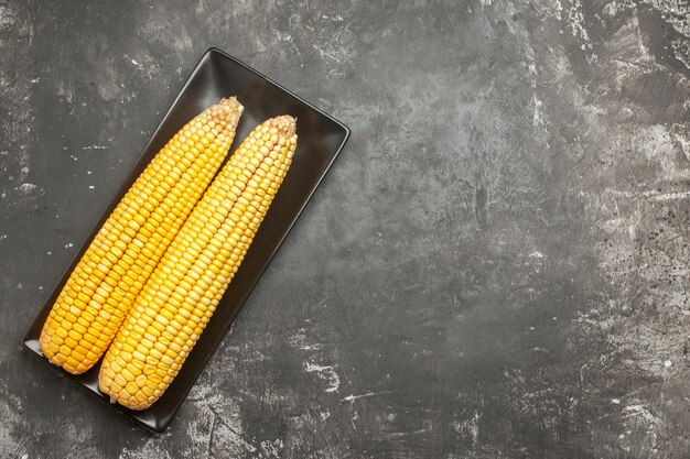 Top view fresh yellow corns inside black pan on dark background