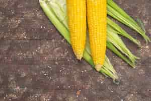 Free photo top view fresh yellow corns with peels on brown food