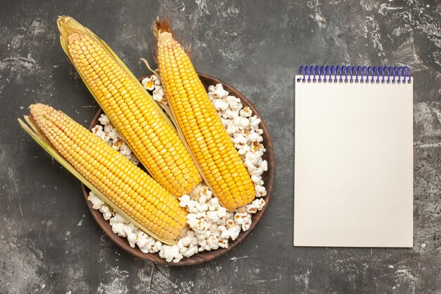 Top view fresh yellow corns with popcorn on a dark background