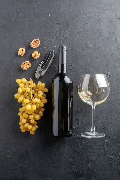 暗いテーブルの上のビュー新鮮な黄色ブドウのワインボトルとガラスワインオープナー