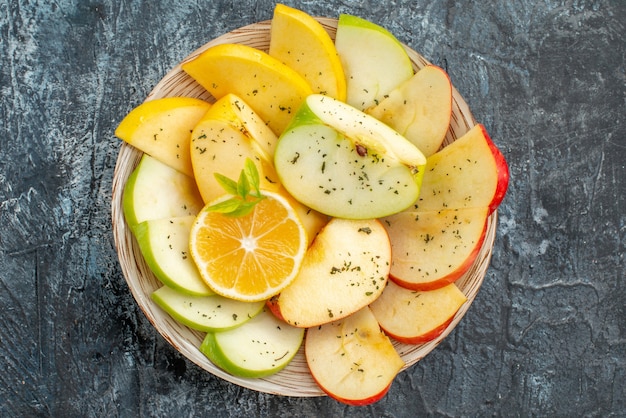 Top view of fresh yellow green red apple slices on a white plate on gray background