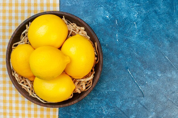 Top view fresh yellow lemons inside plate on blue wall