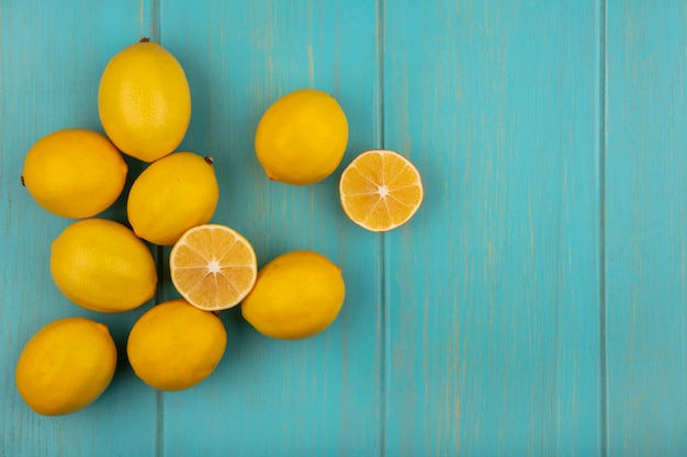 Top view of fresh yellow skinned lemons isolated on a blue wooden background with copy space