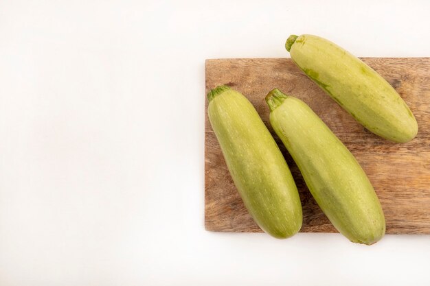 Top view of fresh zucchinis isolated on a wooden kitchen board on a white surface with copy space