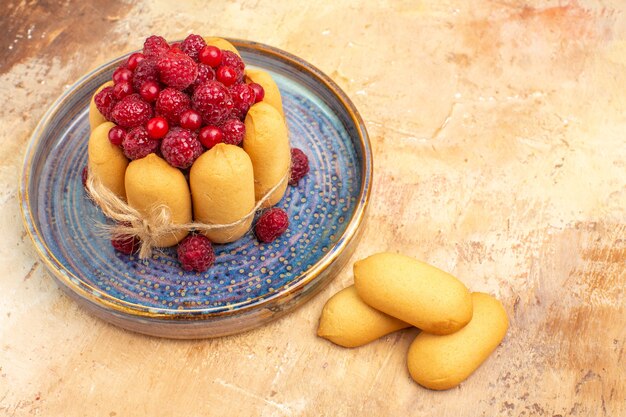 Top view of freshly baked soft cake with fruits and biscuits on mixed color table