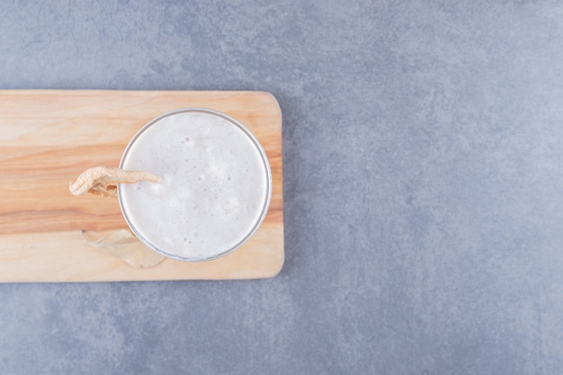 Top view of freshly made milk shake on wooden cutting board.